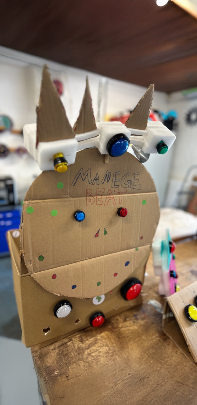 Cardboard beat machine with arcade buttons, labelled MANEGE BEAT