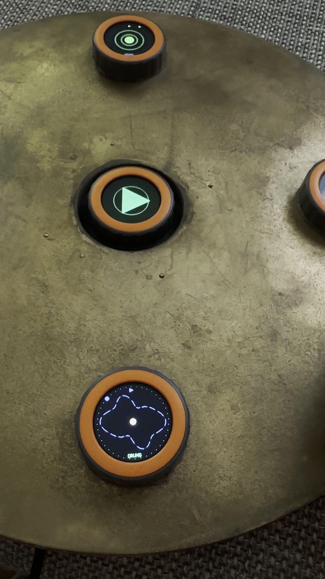 Top view of three discs on the TAMBUM table: concentric green rings at the top, a large play triangle in the middle, a blue wave contour labelled DRUMS at the bottom