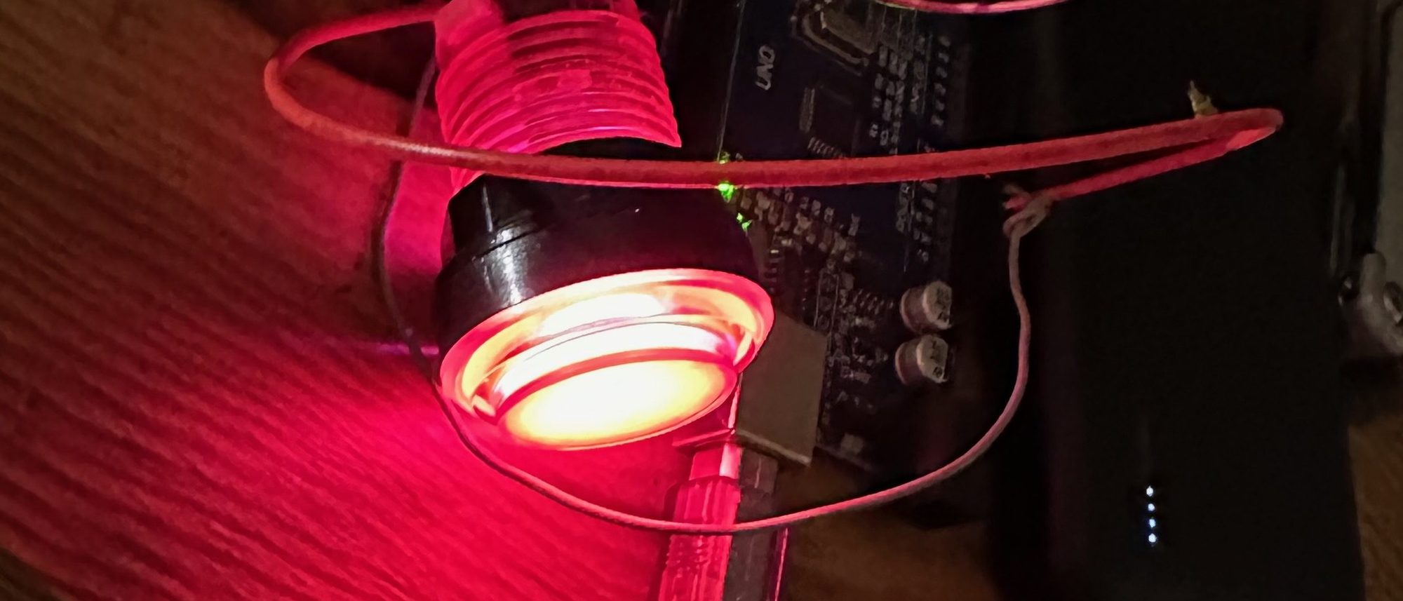 A button glowing red in the darkened workshop