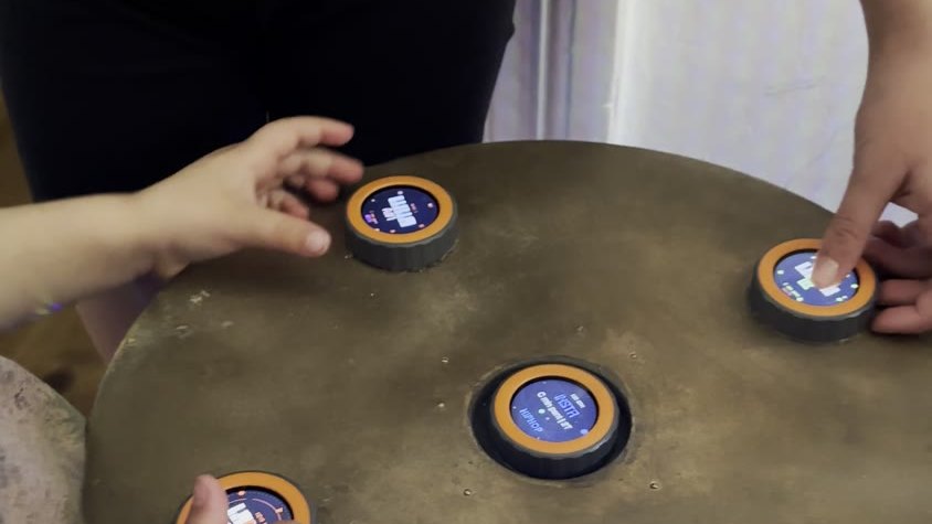 Four discs on the round table, two hands on them