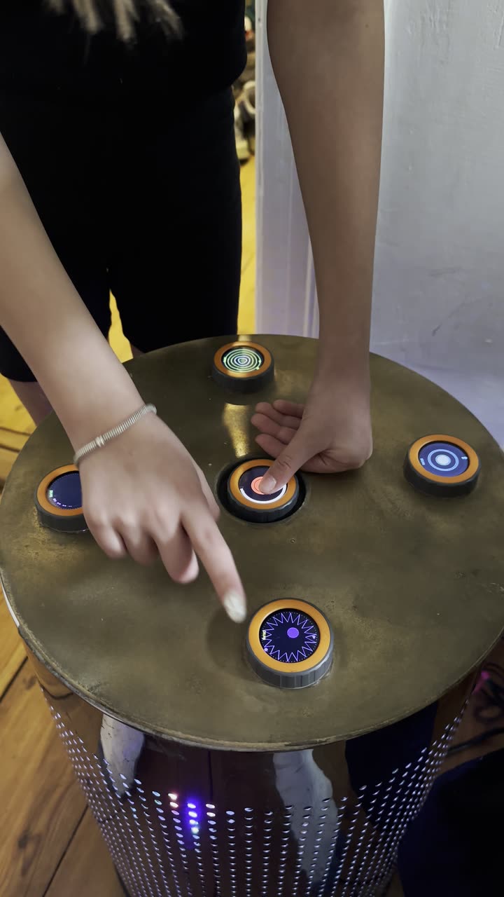 Two pairs of hands playing at the same time on the finished TAMBUM table, the discs lit