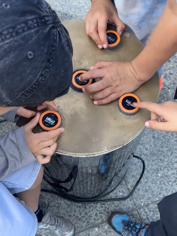 The table from above, children standing all around it and playing; the discs sit in a circle on the top