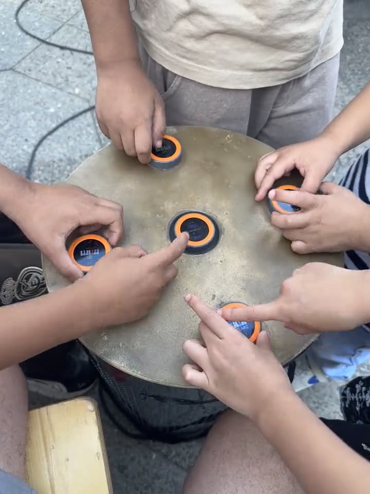 Close-up of the table top from above: several hands resting on different discs at the same time
