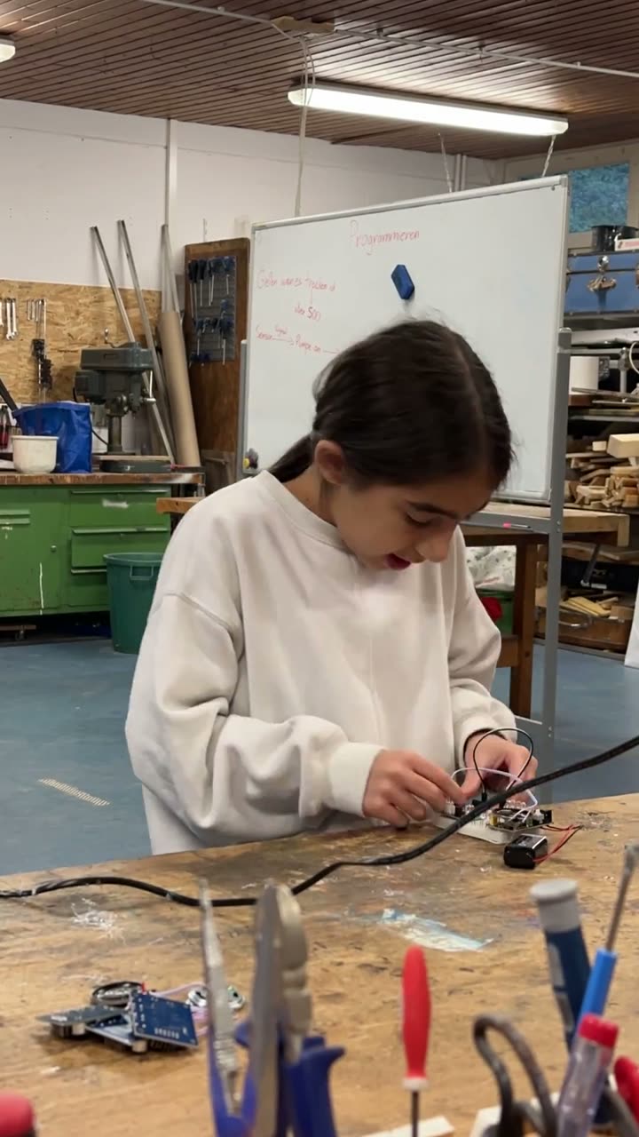 A teenager soldering on a round wooden disc